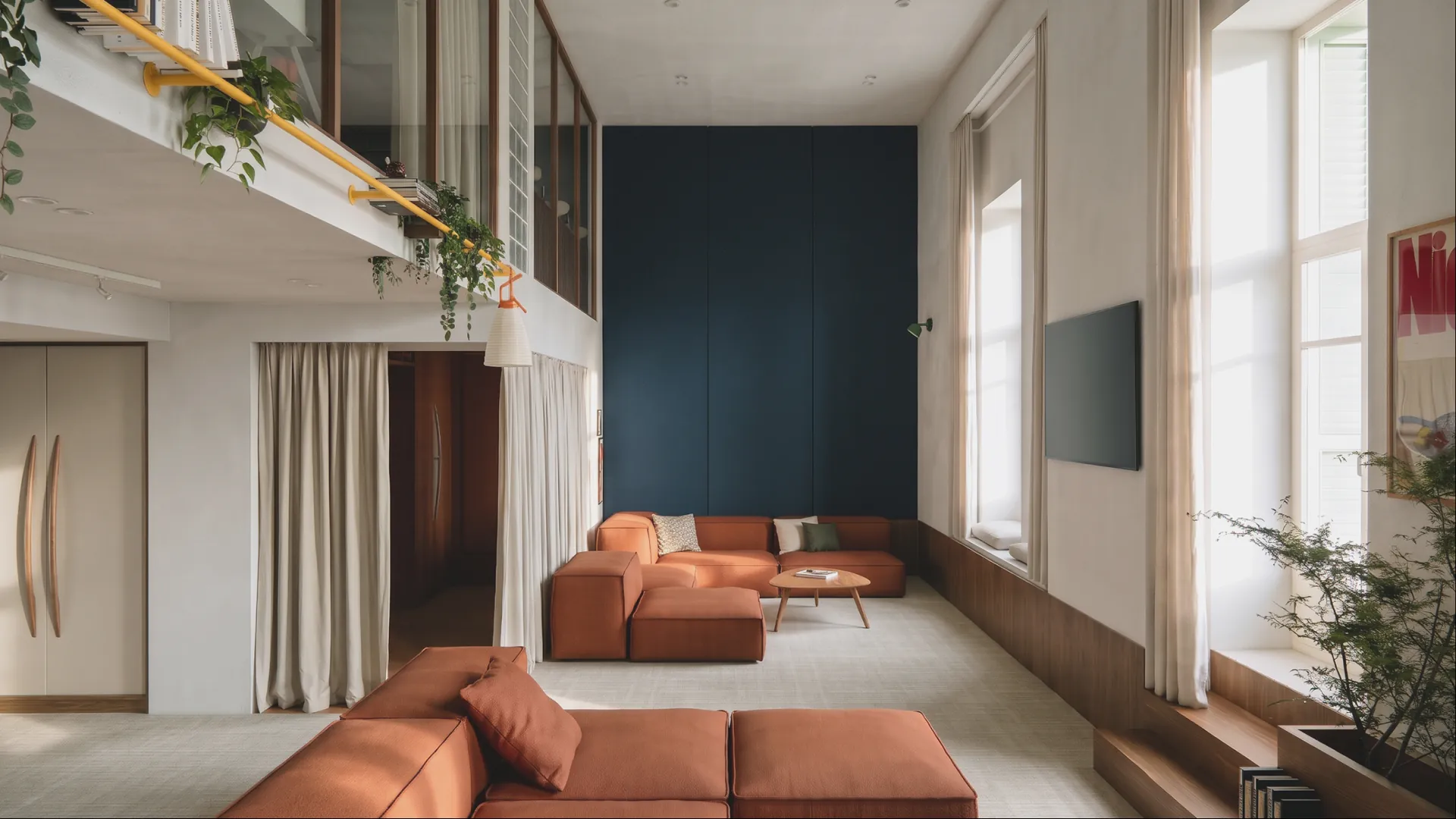 The lounge from the mezzanine stair: sofas, a deep-blue wall and tall windows